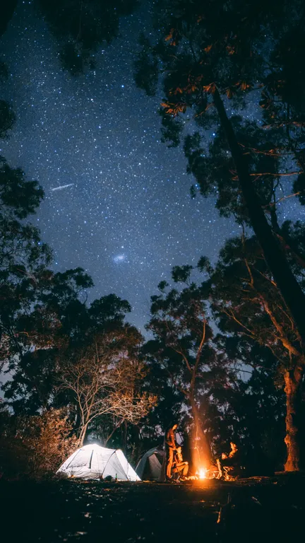 Fogueira à noite sob céu estrelado no acampamento