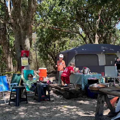 Mesa posta para refeição no acampamento, com a barraca ao fundo