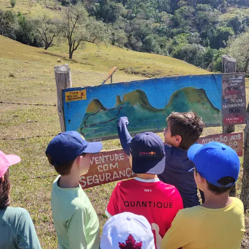 Crianças observando placa de trilhas antes de uma caminhada